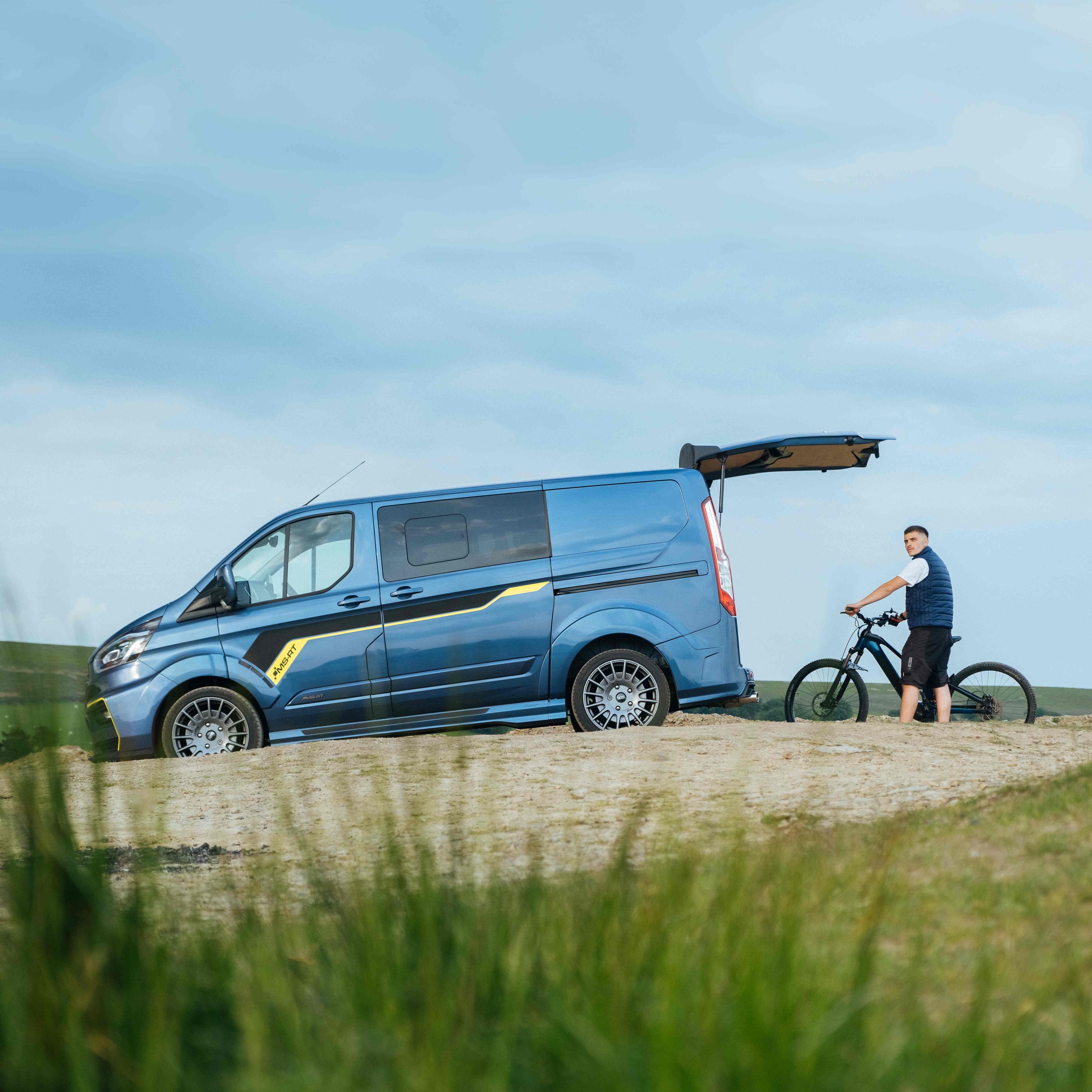 Ford Transit Custom MS-RT with biker holding mountain bike at the rear of the vehicle.